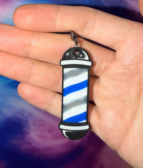 Hand holding a blue and white striped pendant against a tie-dye background